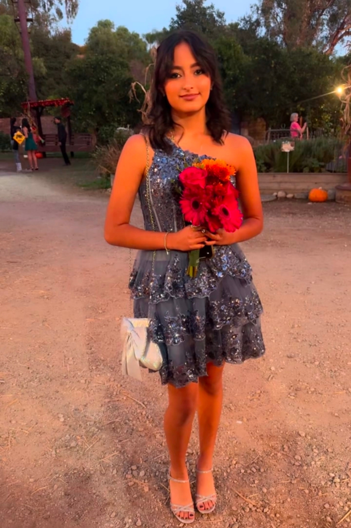 Miah standing in a silver dress holding a bouquet